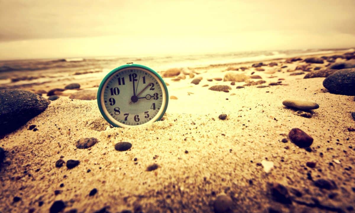 photo clock on the beach time and business concept.